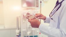 Person wearing stethoscope uses smartphone